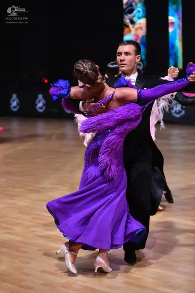 Dancesport competitor: Female dancer: purple sequined ballroom dress with large purple feather trim and