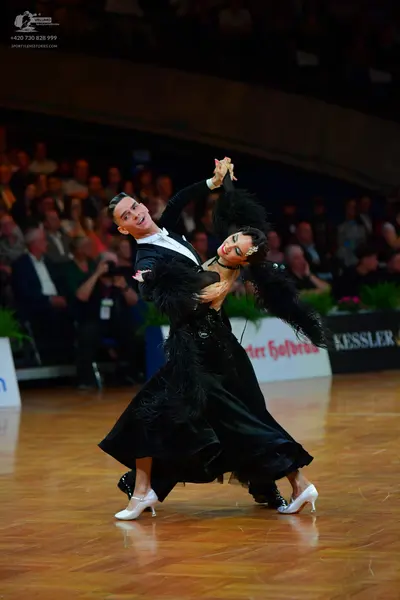 Dancesport competitor: Male dancer: black tuxedo-style suit with a white shirt