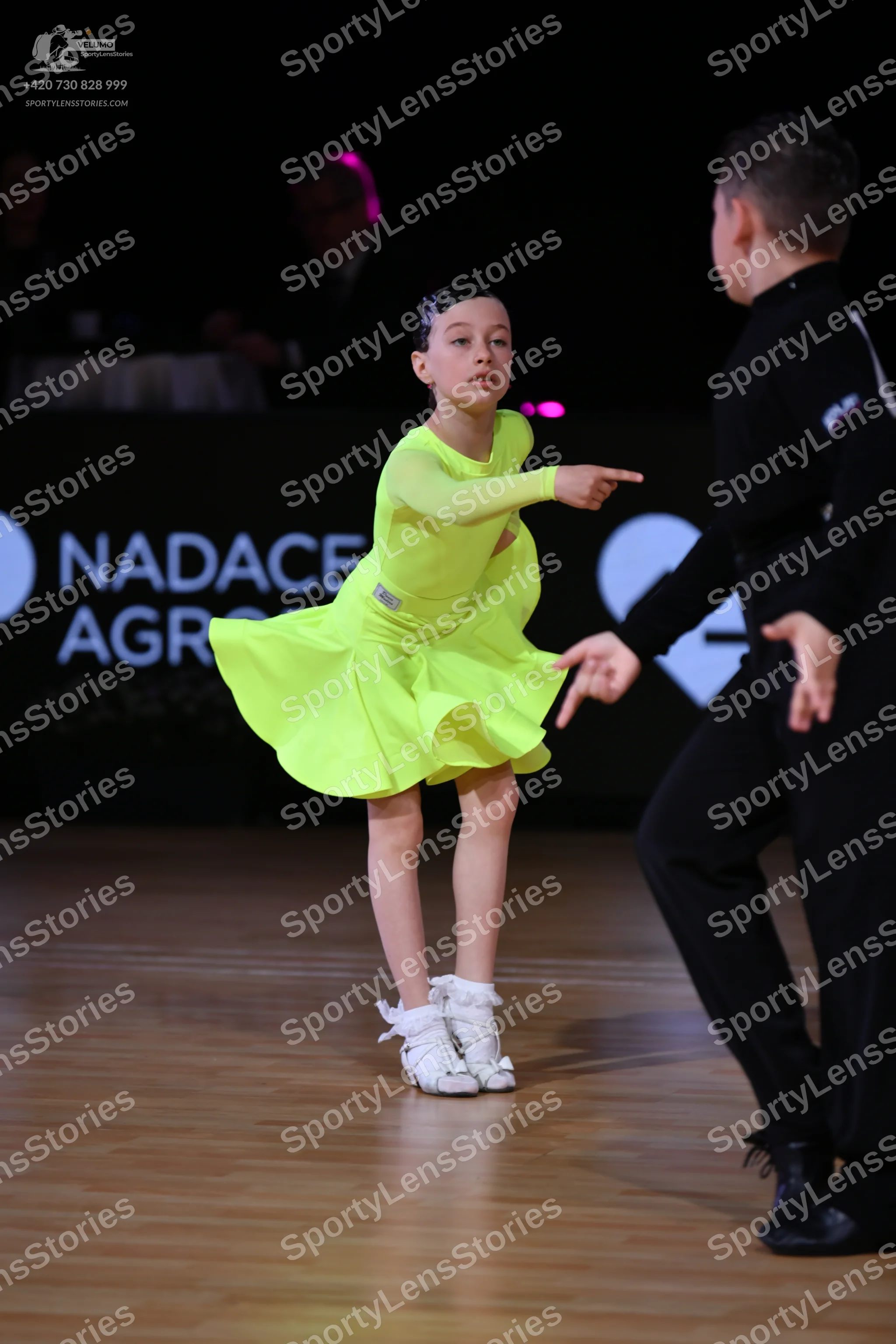 Dancesport competitor: Female dancer: lime green long-sleeved latin dress with a flared skirt and white