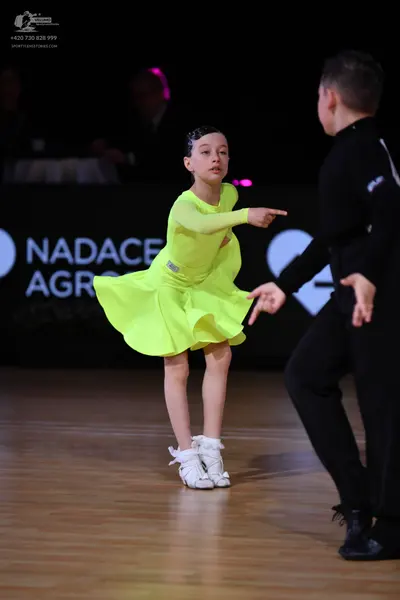Dancesport competitor: Female dancer: lime green long-sleeved latin dress with a flared skirt and white
