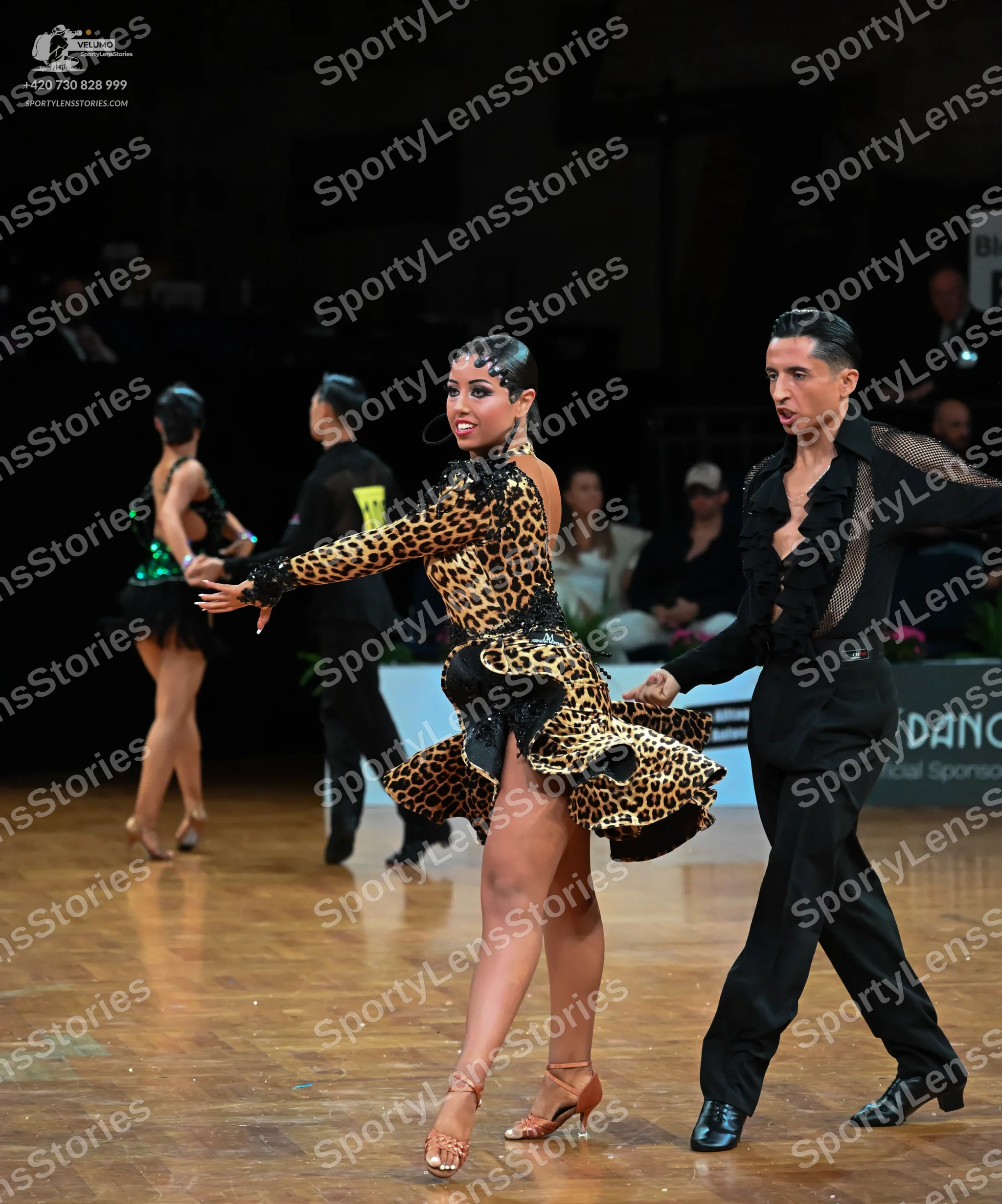 Dancesport competitor: Female dancer: leopard print latin dress with long sleeves, a ruffled hem with b
