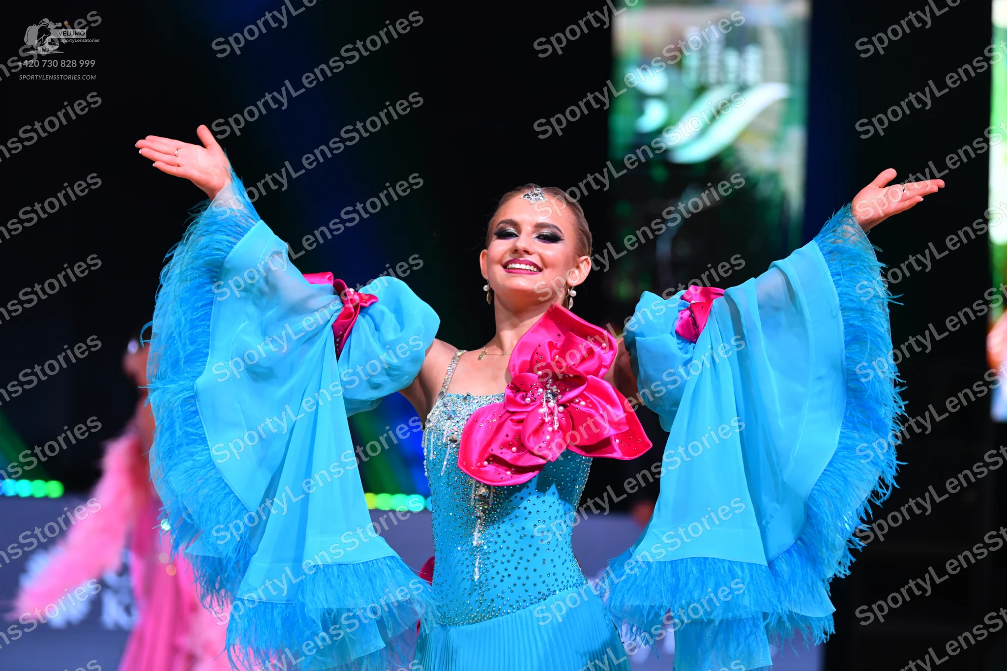 Dancesport competitor: Female dancer: light blue Latin dress with large, voluminous sheer sleeves featu
