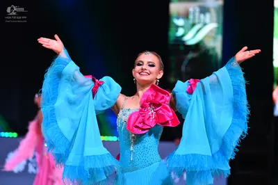Dancesport competitor: Female dancer: light blue Latin dress with large, voluminous sheer sleeves featu
