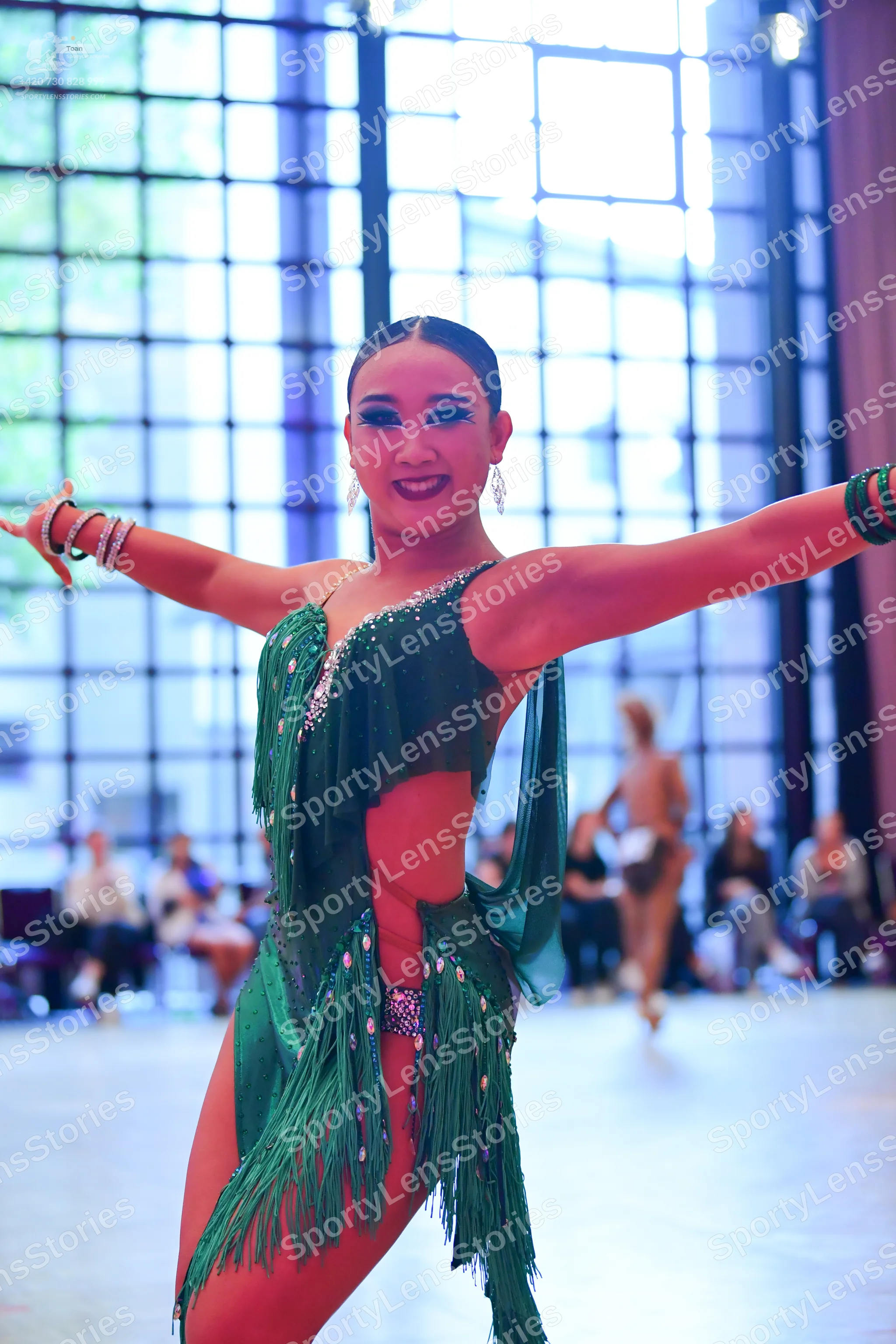 Dancesport competitor: Female dancer: Emerald green Latin dance costume featuring a sequined bodice, cu