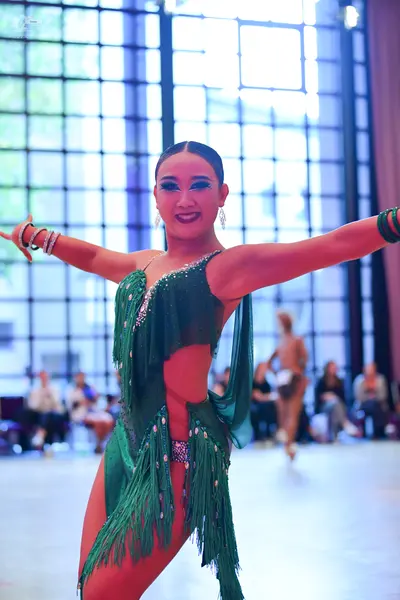 Dancesport competitor: Female dancer: Emerald green Latin dance costume featuring a sequined bodice, cu