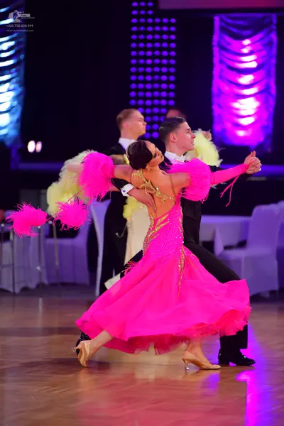 Dancesport competitor: Female dancer: bright pink ballgown with a sequined bodice and voluminous skirt,