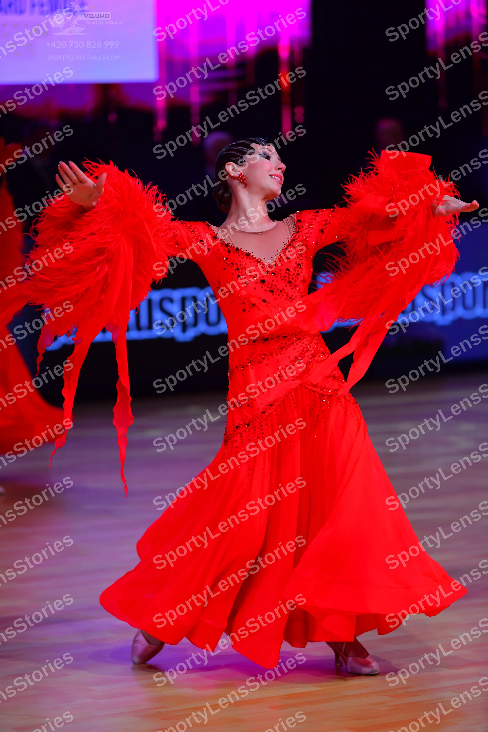 Dancesport competitor: Female dancer: red ballroom dress with a full skirt, large flared sleeves with l