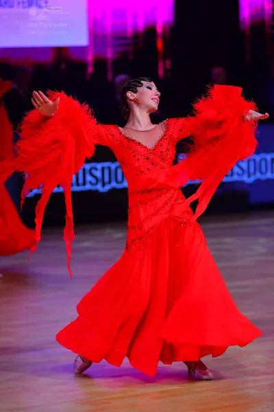 Dancesport competitor: Female dancer: red ballroom dress with a full skirt, large flared sleeves with l