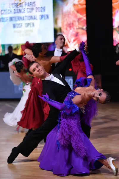 Dancesport competitor: Foreground male dancer: black ballroom suit with a white shirt and white bow tie