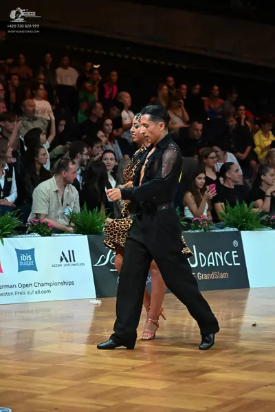 Dancesport competitor: Male dancer: black shirt with sheer sleeves and black trousers
