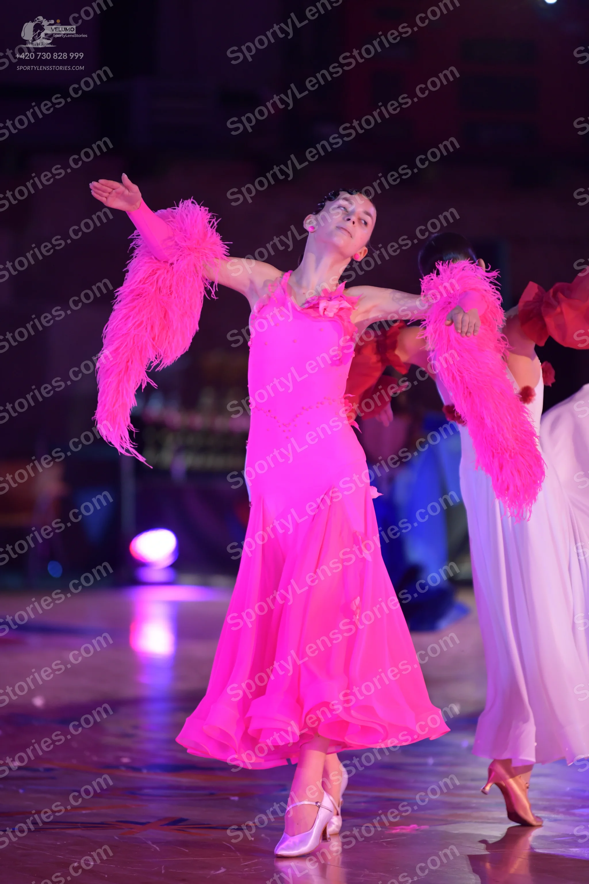 Dancesport competitor: Female dancer: bright pink ballroom dress with a long flowing skirt and large, v