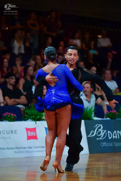 Dancesport competitor: Female dancer: blue long-sleeved latin dress with sequins and blue fringe at the
