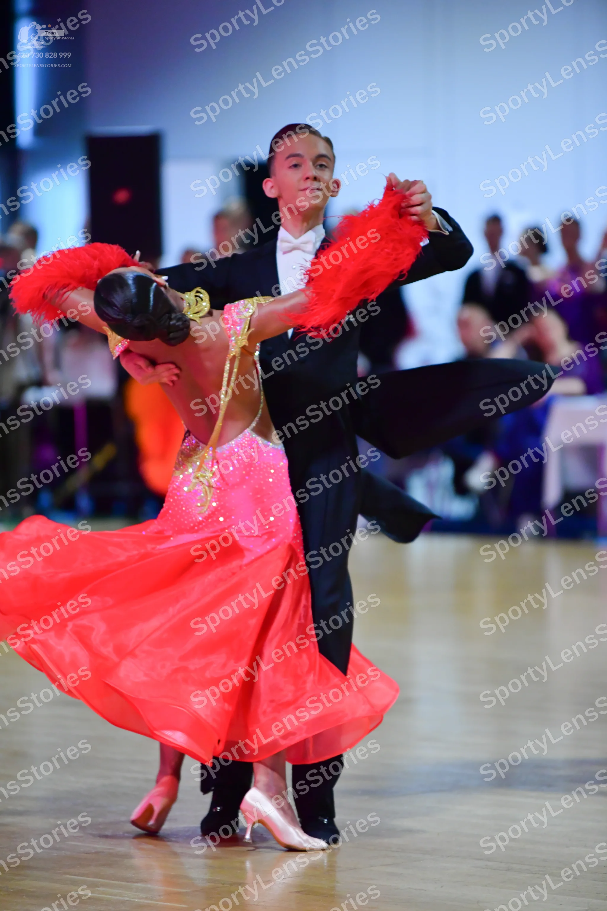 Dancesport competitor: Female dancer: pink/coral ballroom dress with gold sequin detailing, a voluminou