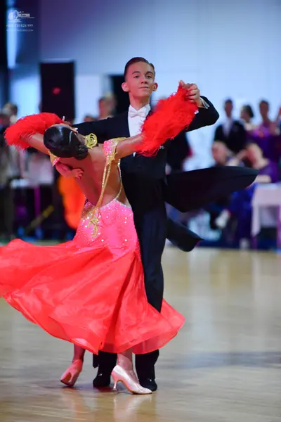 Dancesport competitor: Female dancer: pink/coral ballroom dress with gold sequin detailing, a voluminou
