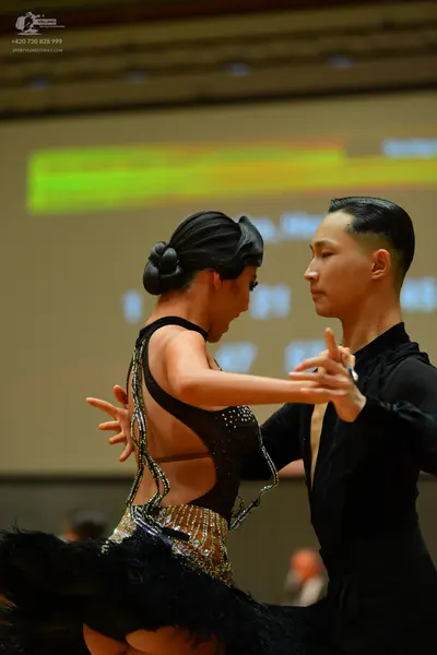 Dancesport competitor: Female dancer: black latin dress with sequin embellishments and large black feat