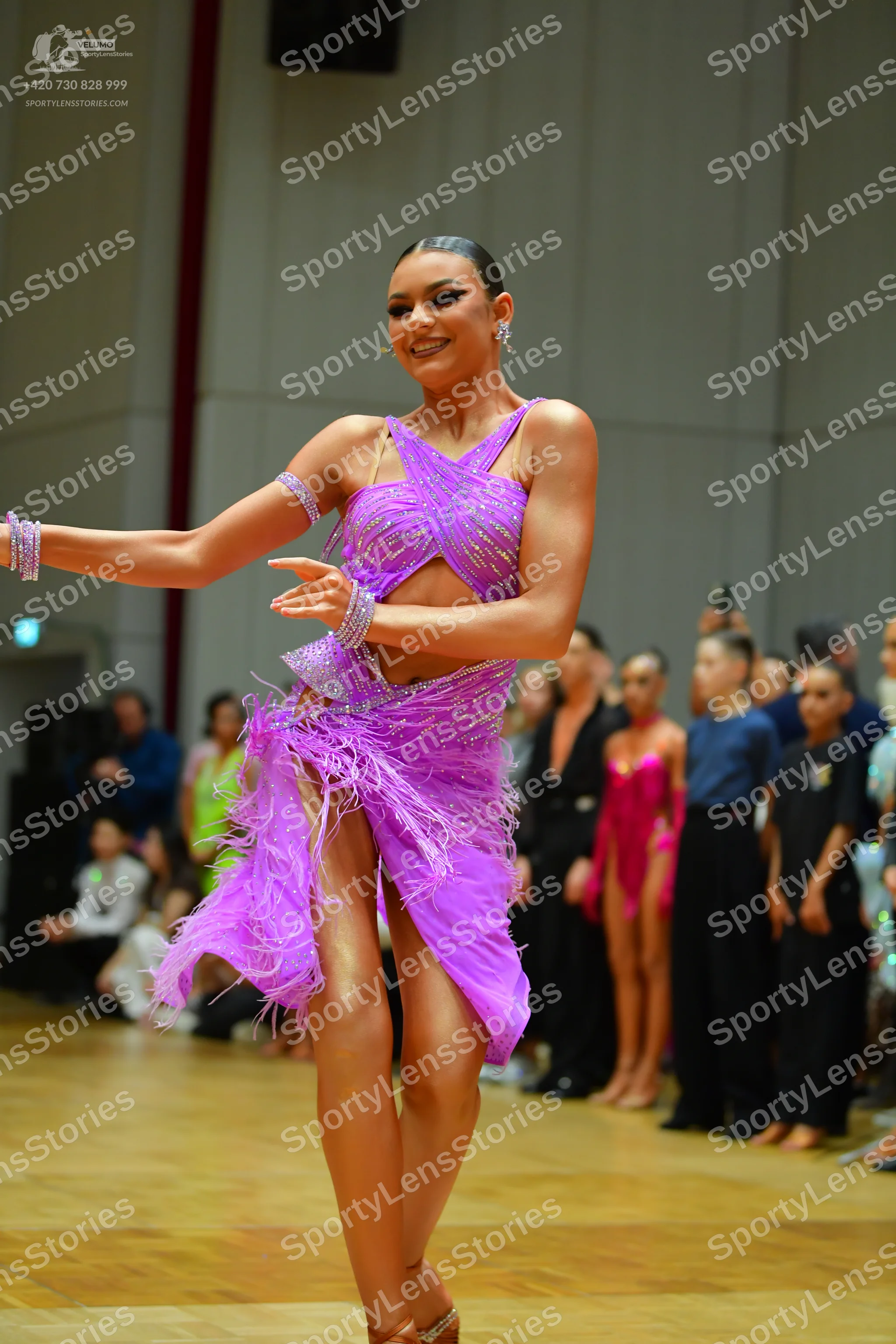Dancesport competitor: Main female dancer: purple latin dress with sequins and fringe, and matching spa