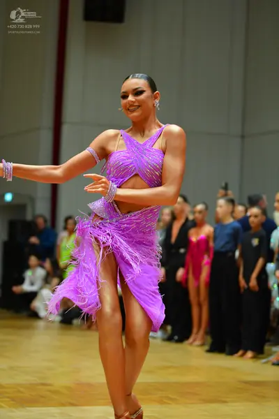 Dancesport competitor: Main female dancer: purple latin dress with sequins and fringe, and matching spa