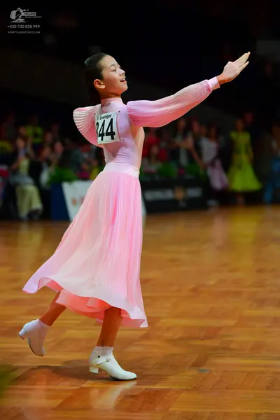 Dancesport competitor: Female dancer: light pink long-sleeved ballroom dress with a pleated midi-length