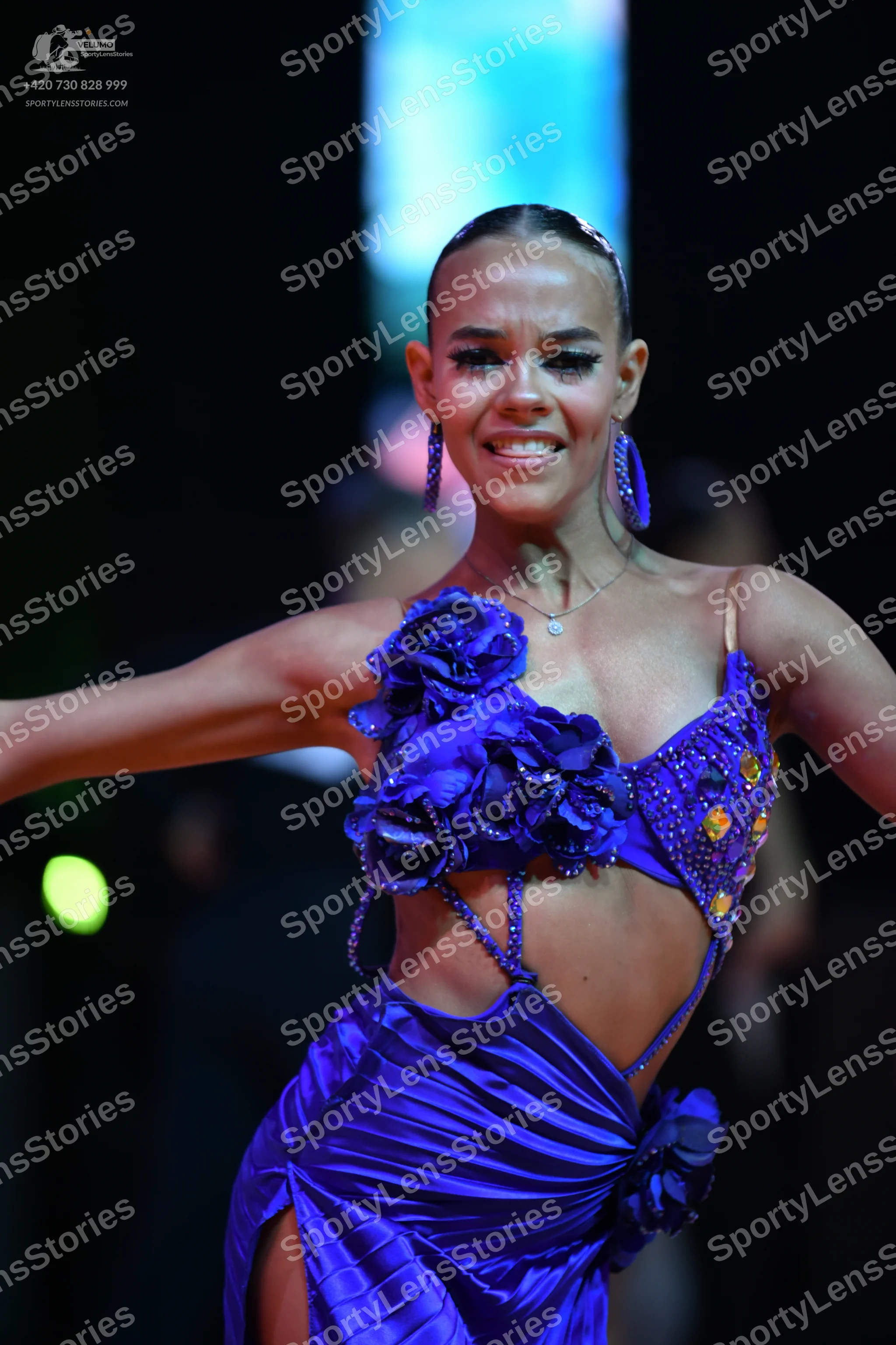 Dancesport competitor: Female dancer: purple latin dress featuring fabric flowers, sequins, and shiny s