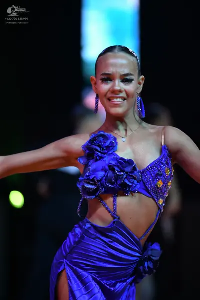 Dancesport competitor: Female dancer: purple latin dress featuring fabric flowers, sequins, and shiny s