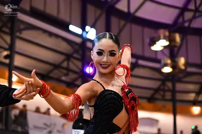Dancesport competitor: Female dancer: black sequin latin dress with red fringe and red hoop earrings