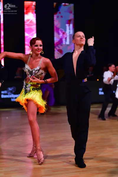 Dancesport competitor: Female dancer: silver sequined Latin dress with bright yellow fringe and large g