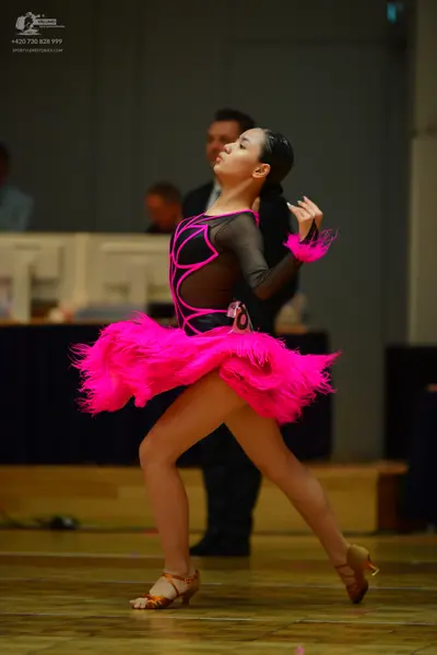 Dancesport competitor #10: Female dancer: black and neon pink Latin dress with sheer mesh panels and a larg