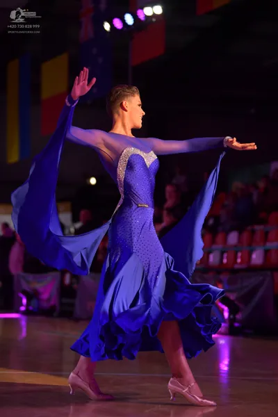 Dancesport competitor: Female dancer: blue ballroom dress with a large, flowing, ruffled skirt, a bodic