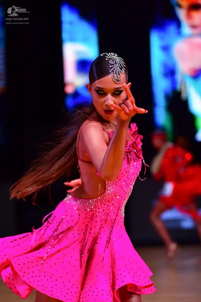 Dancesport competitor: Female dancer in foreground: bright pink latin dress with rhinestone/sequin embe