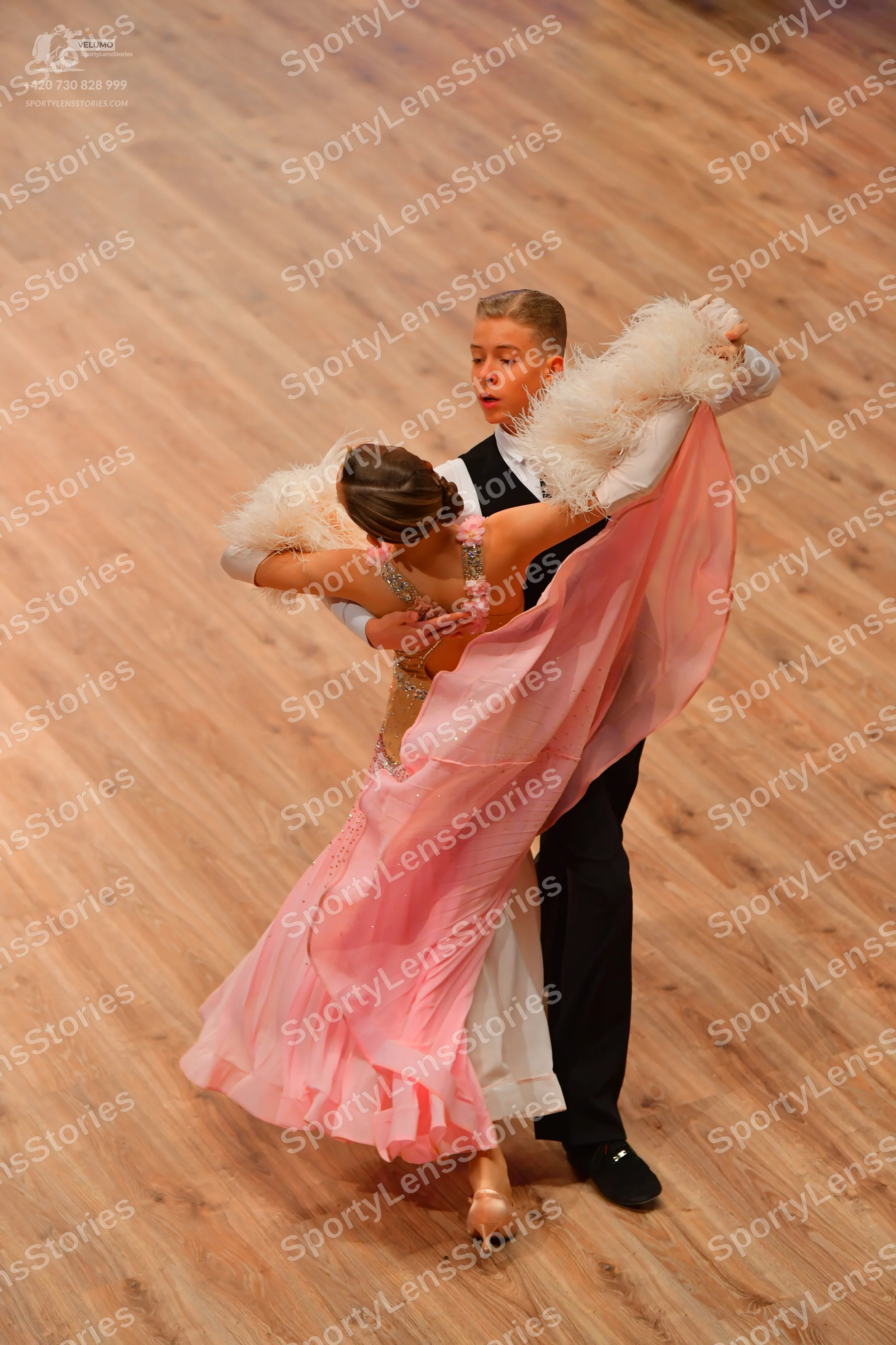 Dancesport competitor: Male dancer: black vest, white long-sleeved shirt with ruffled cuffs, and black