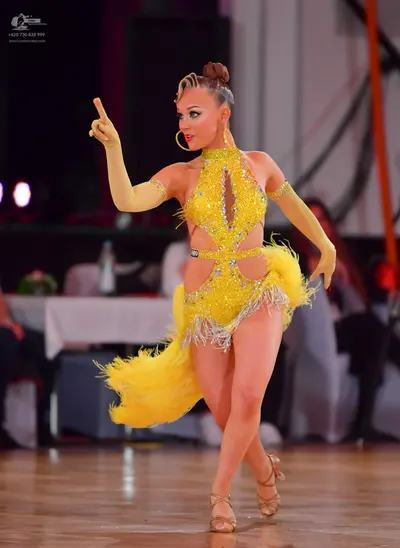 Dancesport competitor: Female dancer: yellow latin dress with sequins and fringe, and long yellow glove