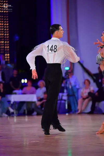 Dancesport competitor #148: Male dancer: white long-sleeved shirt with silver fringe details on the shoulder