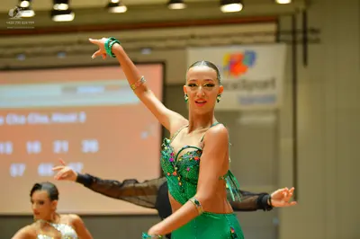 Dancesport competitor: Female dancer in foreground: green sequined Latin dance dress with green bangles