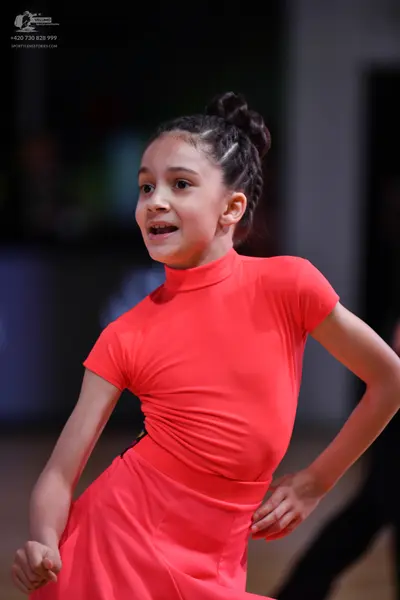 Dancesport competitor: Female dancer: coral-colored latin dress with short sleeves