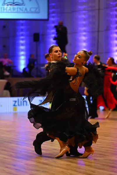 Dancesport competitor: Female dancer: black ballroom gown with voluminous, flowing layers of fabric and