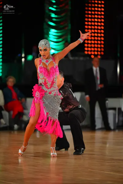 Dancesport competitor: Female dancer: silver sequin Latin dress with bright pink fringe, matching silve