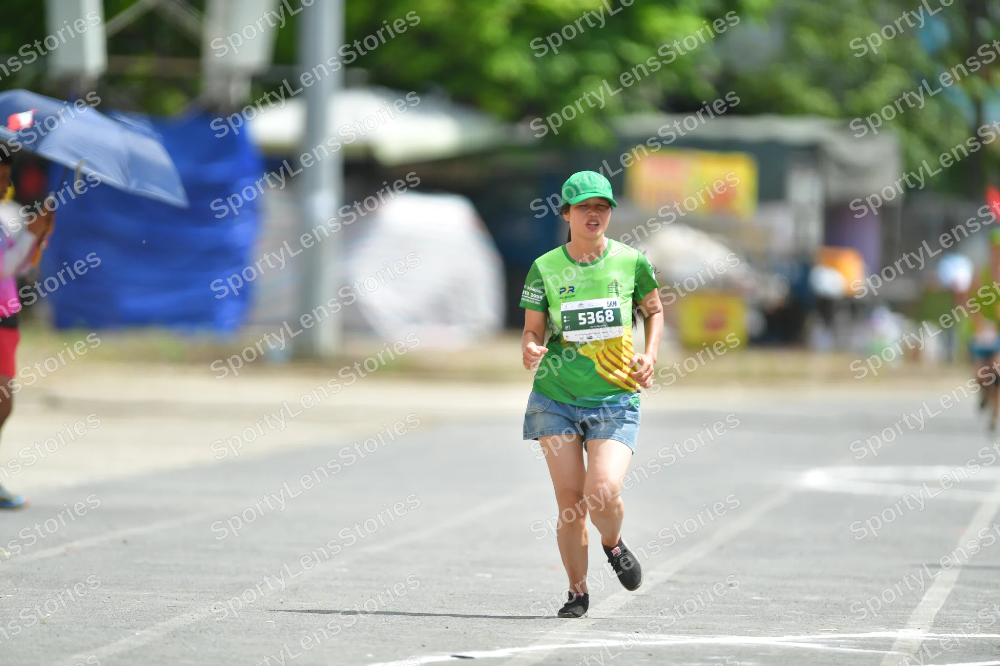 Marathon runner #5368: Runner 1: green jersey, blue shorts, black shoes, green cap