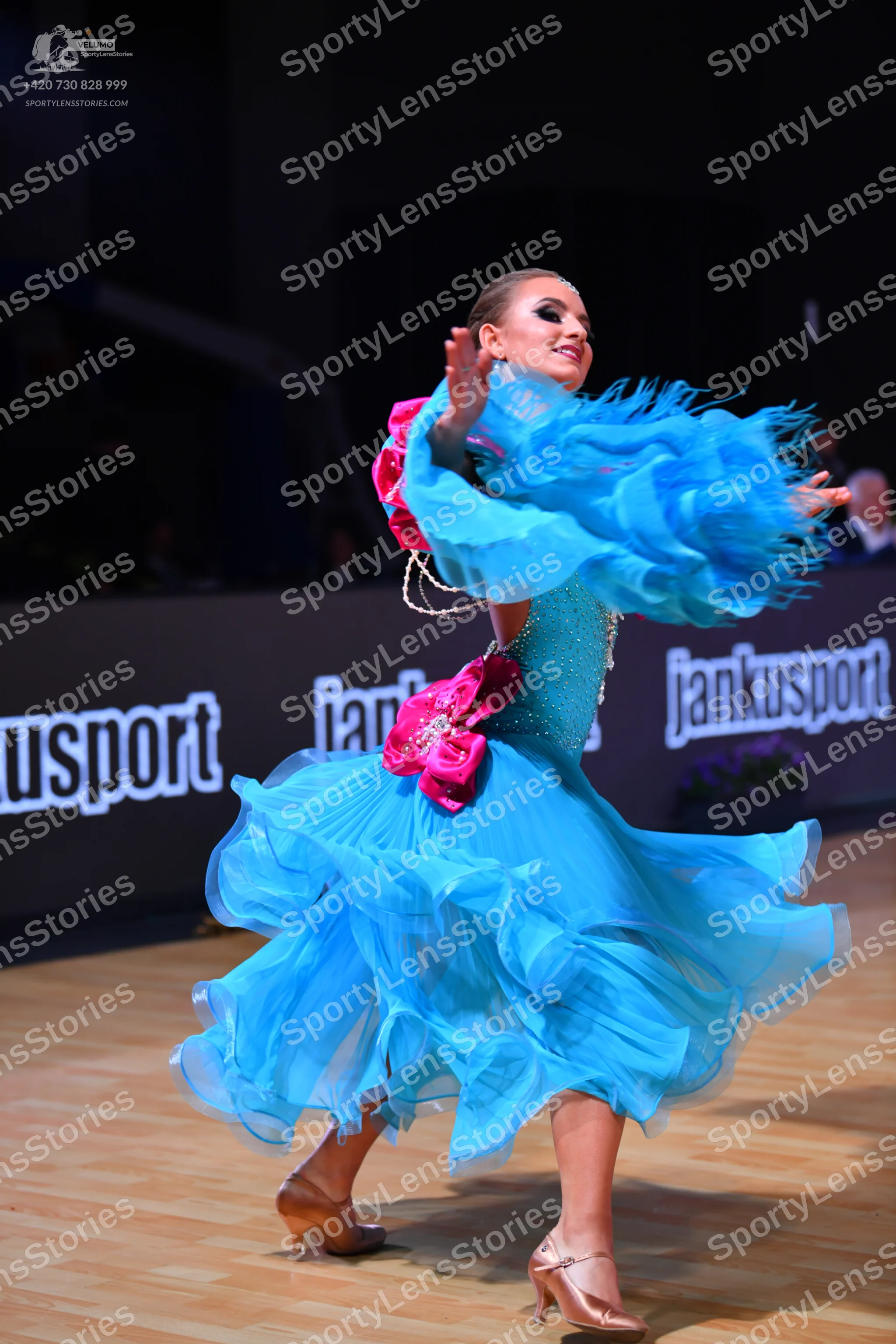 Dancesport competitor: Female dancer: bright blue latin dance dress with a multi-layered, ruffled skirt