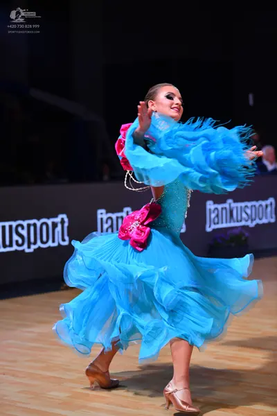 Dancesport competitor: Female dancer: bright blue latin dance dress with a multi-layered, ruffled skirt