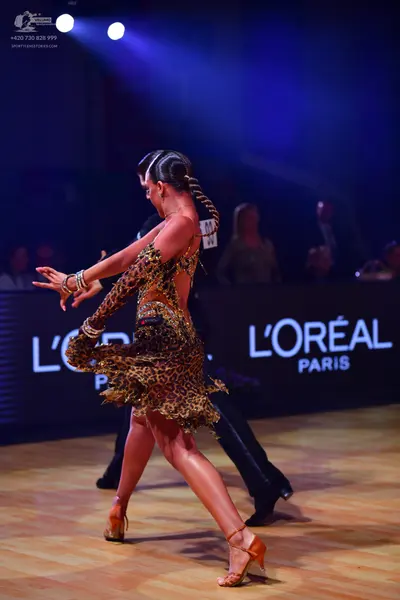 Dancesport competitor: Female dancer: leopard print latin dress with a long sleeve and a fringed, layer
