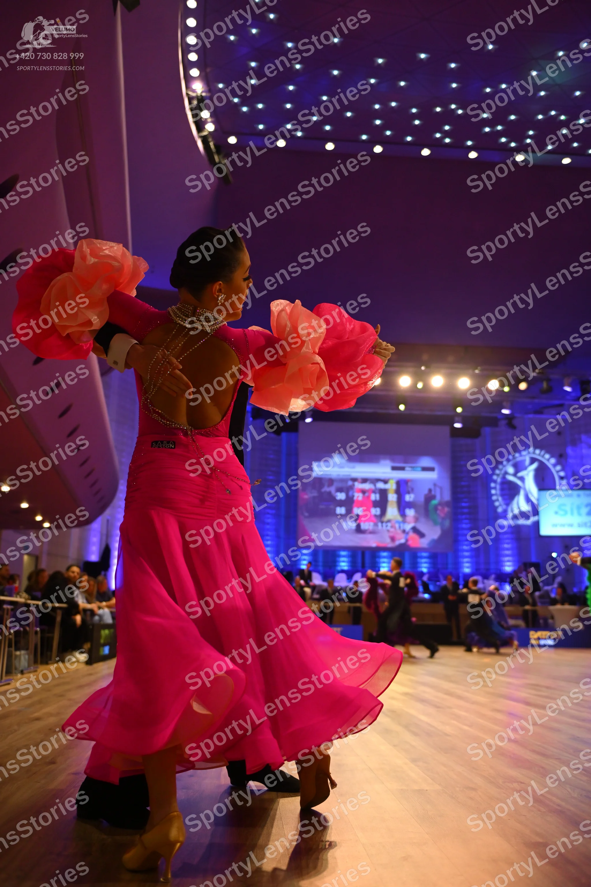 Dancesport competitor: Female dancer: bright pink ballroom dress with large, voluminous, peach-colored 