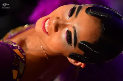 Dancesport competitor: Female dancer: purple costume with large, reflective, jewel-like embellishments