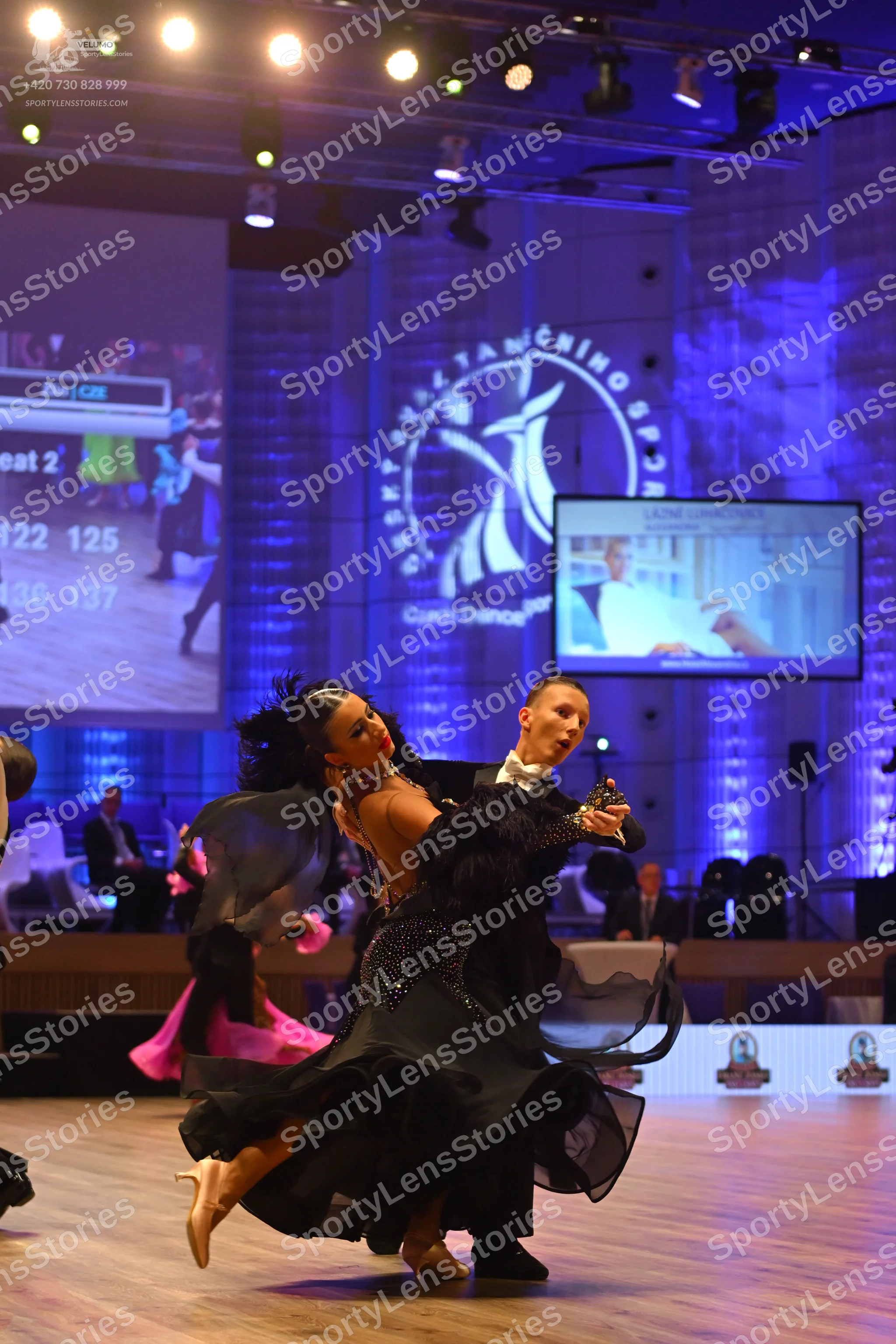 Dancesport competitor: Female dancer: black ballroom dress with a voluminous skirt and feathered or ruf