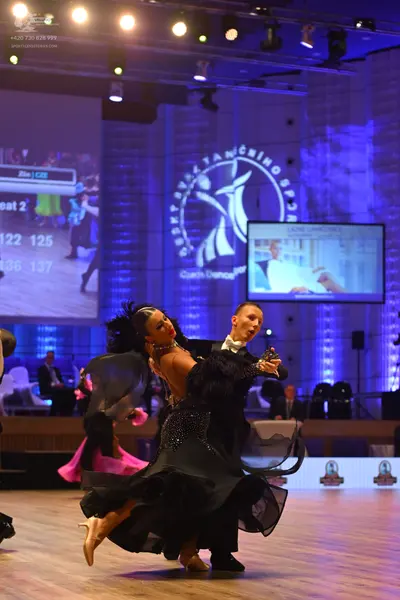 Dancesport competitor: Female dancer: black ballroom dress with a voluminous skirt and feathered or ruf