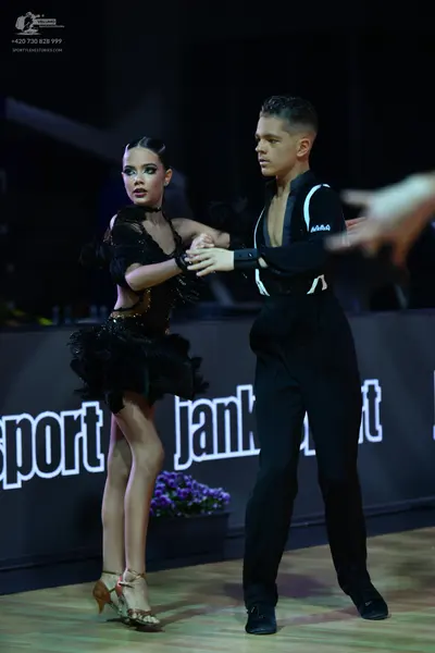 Dancesport competitor: Female dancer: black latin dress with ruffled skirt and sequin details, black ch