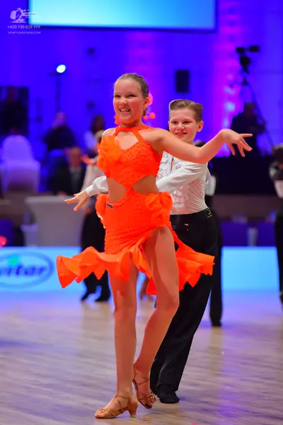 Dancesport competitor: Female dancer: orange latin dress with cutouts and ruffled hem