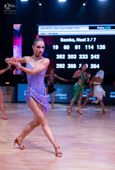 Dancesport competitor: Female dancer in foreground: purple sequin Latin dress with fringe, sparkly neck