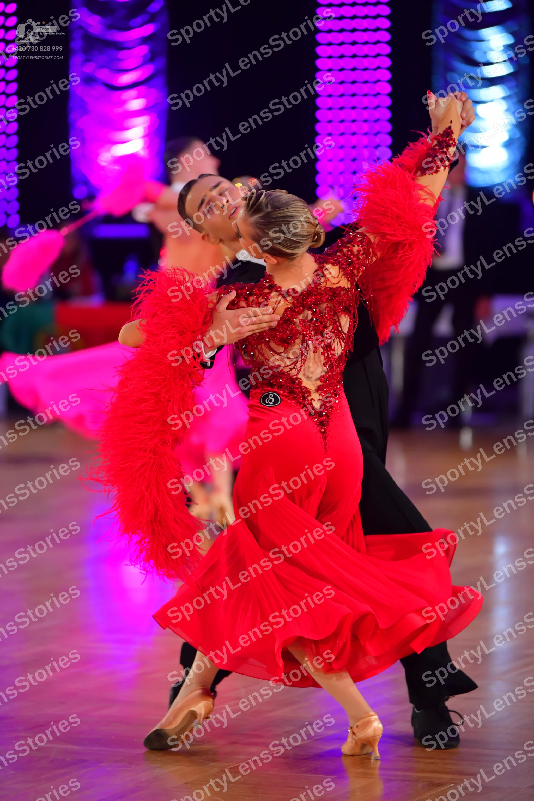 Dancesport competitor: Female dancer: red latin dress with a lace-detailed bodice and large, voluminous