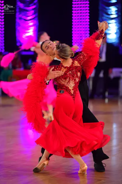 Dancesport competitor: Female dancer: red latin dress with a lace-detailed bodice and large, voluminous