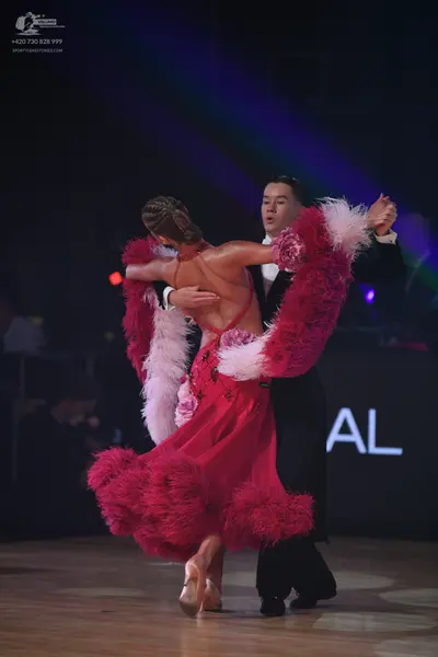Dancesport competitor: Female dancer: magenta Latin dress featuring large pink and white feathered trim